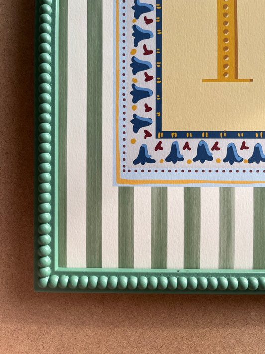 Nursery alphabet wall art featuring the letter of your choice a golden serif font with decorative block-print inspired folk floral border and a muted green striped background, perfect for baby room decor, personalized children’s wall art, alphabet nursery print, gender-neutral baby gift, Montessori room decor, educational wall art, and unique custom gift ideas for kids