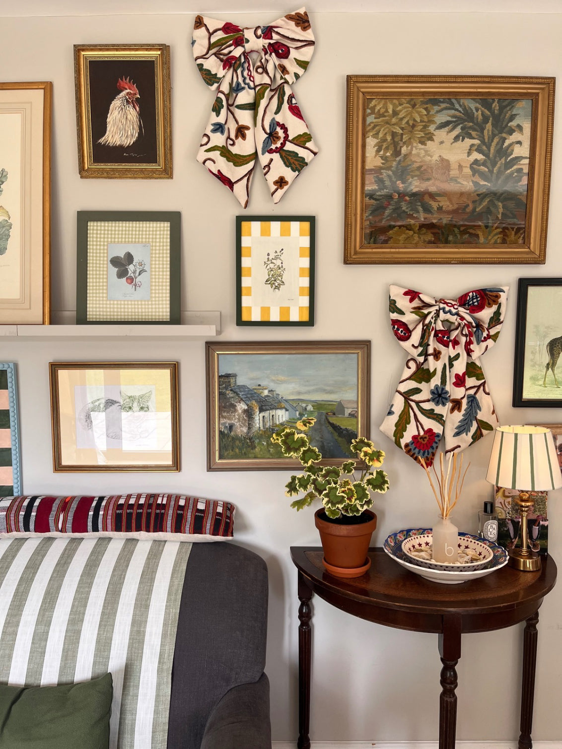 Hand-embroidered vintage fabric crewel work bow with vibrant floral and vine motifs in red, green, blue, and ochre, styled in a traditional countryside cotswold home — perfect as a decorative accent for furniture,  door knobs, the garden or seasonal home styling, it would also make a unique gift or wall decor 