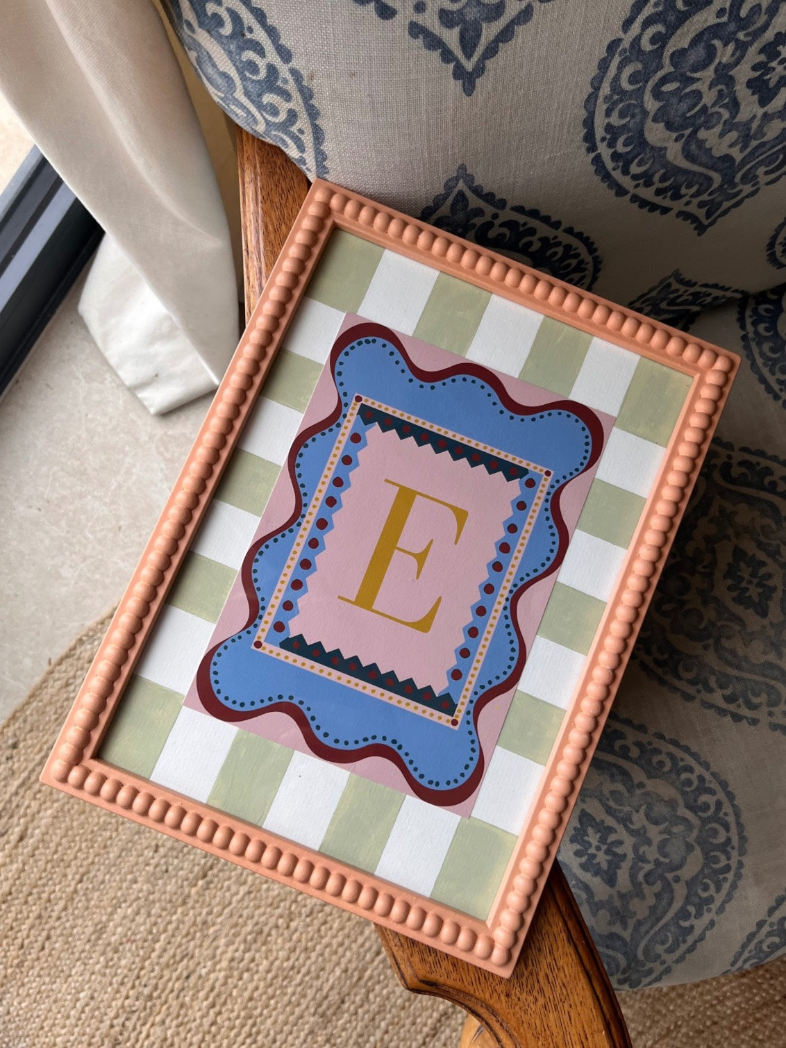 Playful alphabet wall art featuring the letter ‘H’ in a bold gold font, set against a pink and blue patterned background with wavy borders. Paired here with a hand painted stripy picture mount in light green and a peach bobbin frame. Perfect as a decorative nursery or children’s bedroom/playroom print and a charming, unique gift idea for adults and kids alike. 