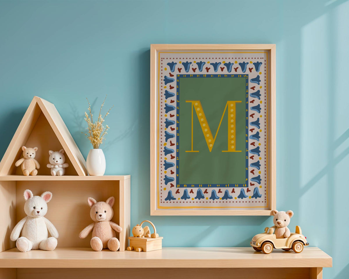Personalised vintage initial letter print featuring a mustard yellow alphabet letter on a muted sage green background with blue floral border and dusty red striped detailing, styled in a light wooden frame for a gender-neutral nursery or children's bedroom.